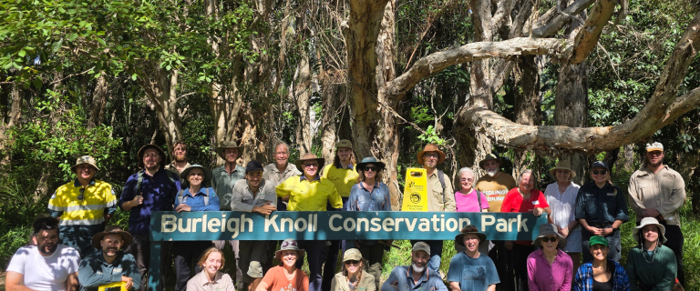 A group of conservation volunteers around the Burleigh Knoll Conservation Park sign, smiling at the launch event.
